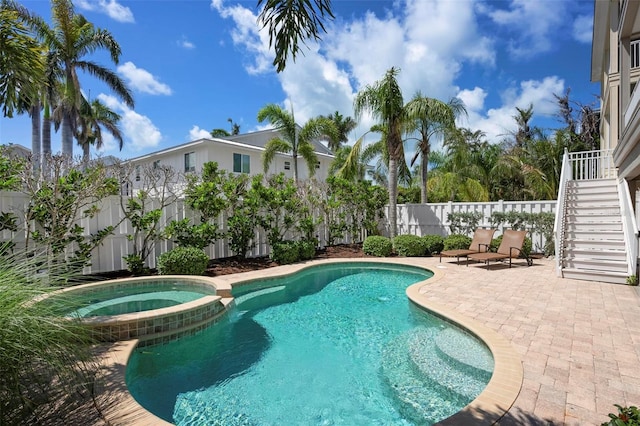 view of swimming pool featuring stairway, a patio area, a fenced backyard, and a pool with connected hot tub