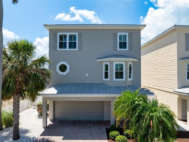 view of front of property featuring a standing seam roof, a garage, metal roof, and fence