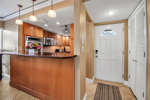 10423 Waterbird Way Unit 10423, Bradenton, FL 34209 - kitchen featuring appliances with stainless steel finishes, light tile patterned floors, baseboards, dark countertops, and brown cabinetry