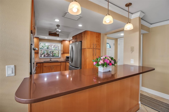 10423 Waterbird Way Unit 10423, Bradenton, FL 34209 - kitchen with freestanding refrigerator, brown cabinetry, a sink, ornamental molding, and a ceiling fan