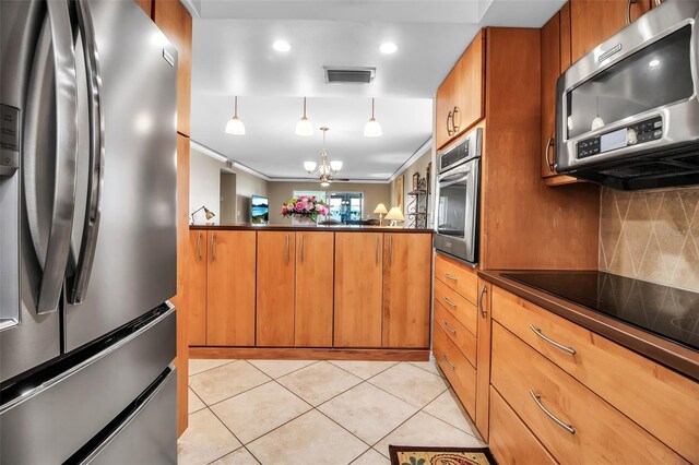 10423 Waterbird Way Unit 10423, Bradenton, FL 34209 - kitchen with appliances with stainless steel finishes, dark countertops, brown cabinets, light tile patterned floors, and a chandelier