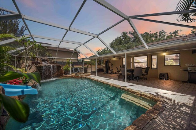 4225 Ulman Ave, North Port, FL 34286 - pool at dusk with a ceiling fan, a patio, outdoor dining area, a pool with connected hot tub, and area for grilling