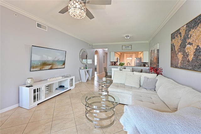 living room featuring a ceiling fan, arched walkways, ornamental molding, light tile patterned floors, and baseboards