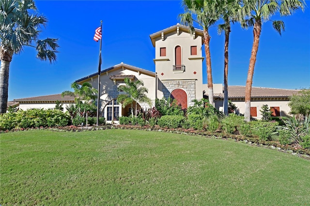 mediterranean / spanish home with a front lawn, stucco siding, and stone siding