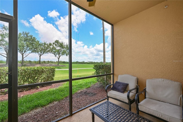 sunroom / solarium featuring view of golf course and healthy amount of natural light