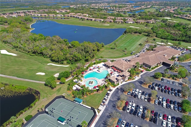 aerial view of property and surrounding area featuring a nearby body of water, a golf course, and a pool area
