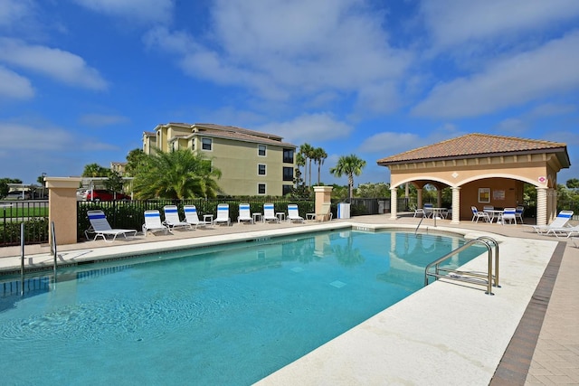 community pool featuring fence and a patio area
