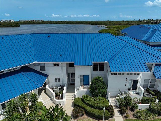 view of front of home with metal roof, stairway, a standing seam roof, and a water view