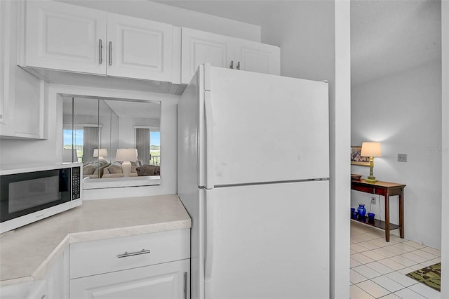 kitchen with white appliances, light countertops, white cabinets, and light tile patterned flooring