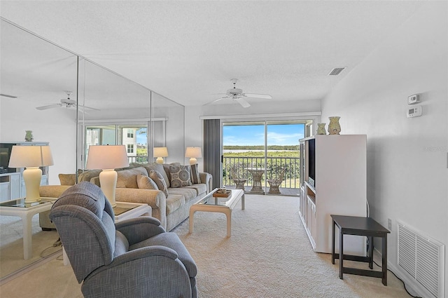 living room with ceiling fan, light colored carpet, plenty of natural light, and a textured ceiling