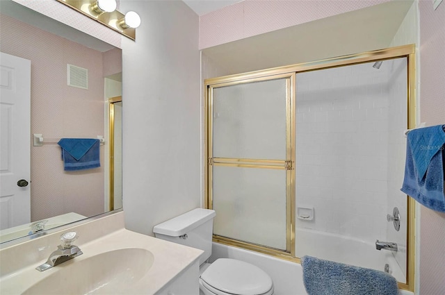 bathroom with toilet, enclosed tub / shower combo, and vanity