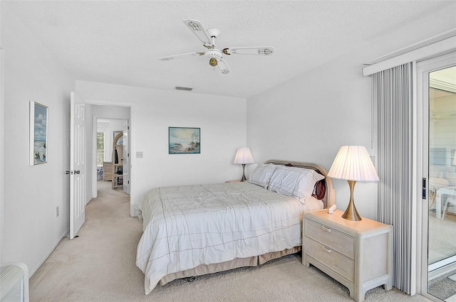 bedroom with light carpet, a textured ceiling, and a ceiling fan