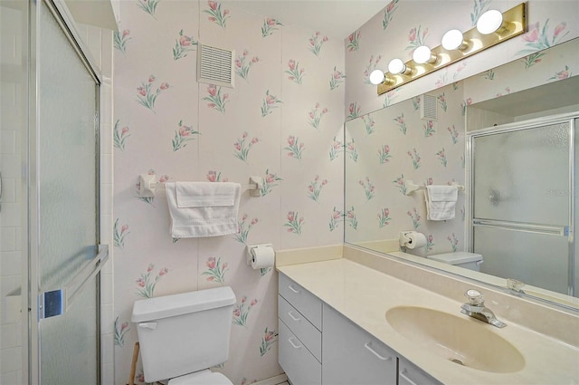 bathroom with toilet, wallpapered walls, a shower with door, and vanity