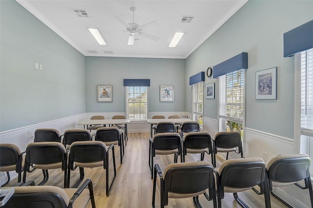 miscellaneous room featuring a ceiling fan, light wood finished floors, wainscoting, and ornamental molding