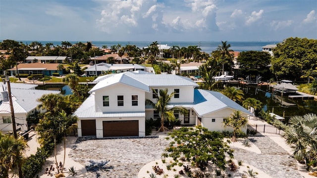 603 Emerald Ln, Holmes Beach, FL 34217 - view of front facade featuring a garage, a water view, fence, metal roof, and driveway