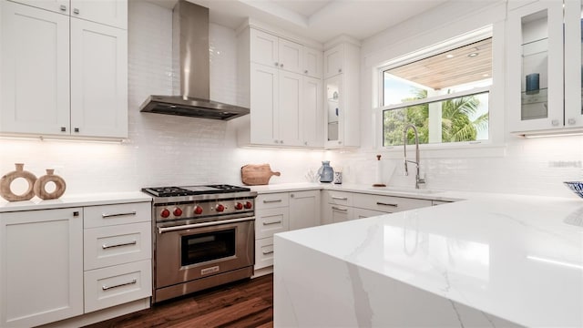 603 Emerald Ln, Holmes Beach, FL 34217 - kitchen featuring wall chimney exhaust hood, designer stove, a sink, decorative backsplash, and white cabinetry