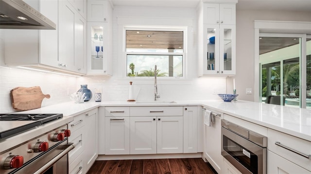 603 Emerald Ln, Holmes Beach, FL 34217 - kitchen with under cabinet range hood, appliances with stainless steel finishes, dark wood-style floors, light countertops, and white cabinets