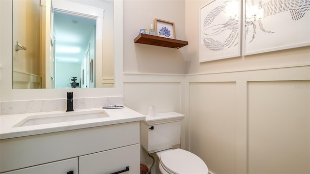 603 Emerald Ln, Holmes Beach, FL 34217 - half bath featuring vanity, toilet, a wainscoted wall, and a decorative wall