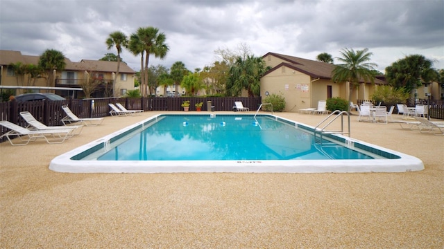 community pool with a patio and fence