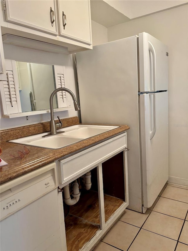 kitchen featuring white appliances, a sink, light tile patterned flooring, white cabinets, and dark countertops