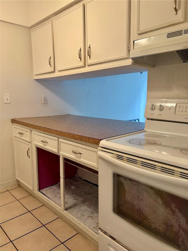kitchen with white electric stove, under cabinet range hood, white cabinets, and light tile patterned floors