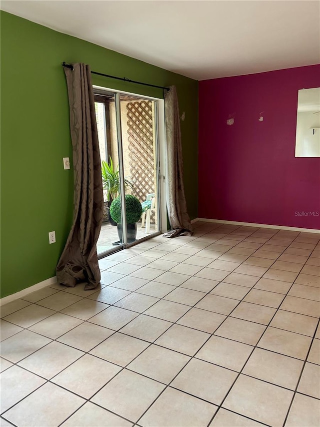 spare room with baseboards and light tile patterned flooring