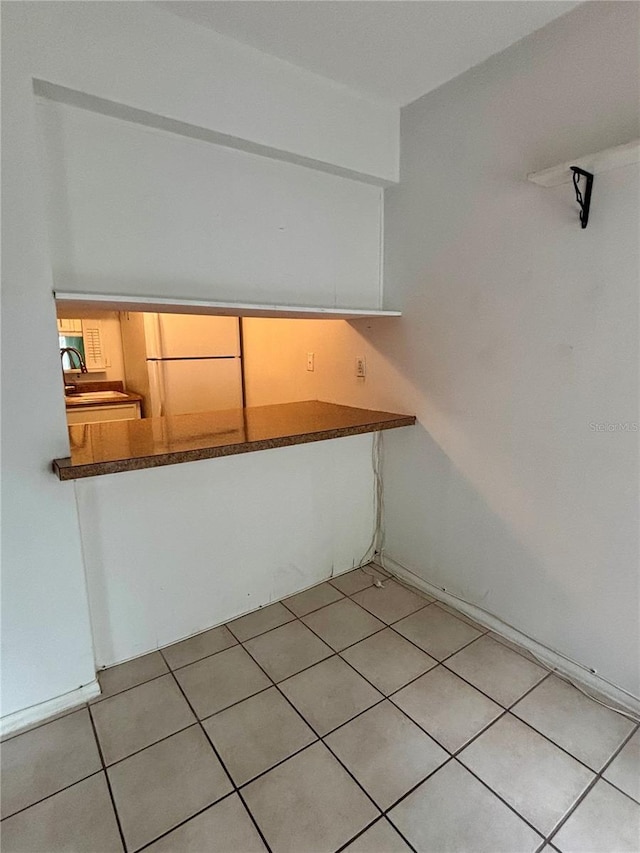 empty room with light tile patterned floors and a sink