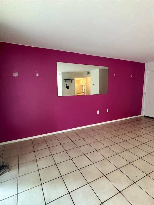 spare room featuring baseboards and light tile patterned flooring