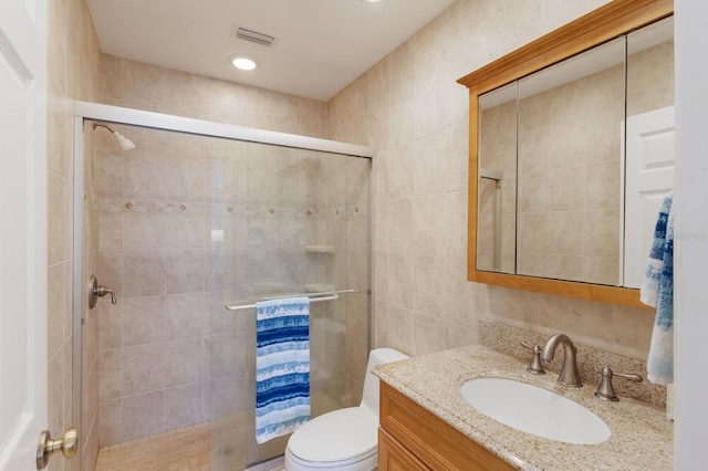 bathroom with tile walls, a stall shower, vanity, and toilet