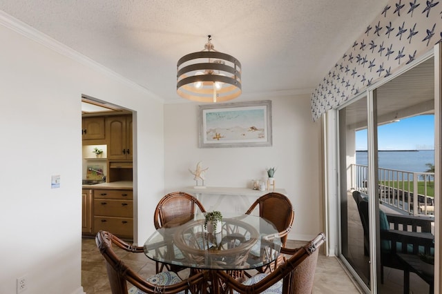 dining room with a chandelier, a water view, ornamental molding, a textured ceiling, and light tile patterned floors