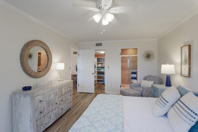 bedroom with crown molding, a walk in closet, light wood-style flooring, connected bathroom, and ceiling fan