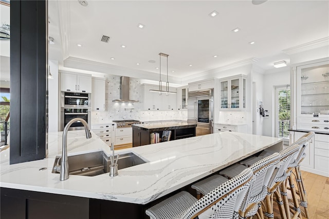 kitchen featuring stainless steel appliances, wall chimney exhaust hood, ornamental molding, a spacious island, and backsplash