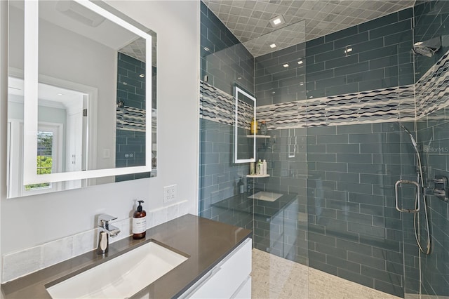 full bathroom featuring tiled shower and vanity