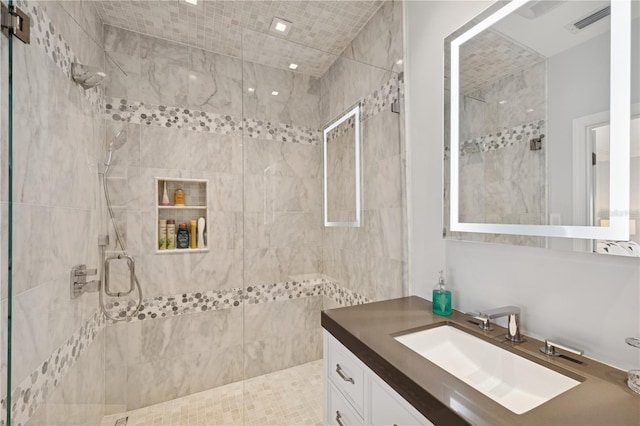 full bathroom with a tile shower and vanity