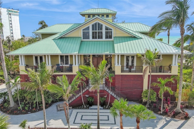 view of front facade featuring metal roof, covered porch, stairs, a standing seam roof, and french doors
