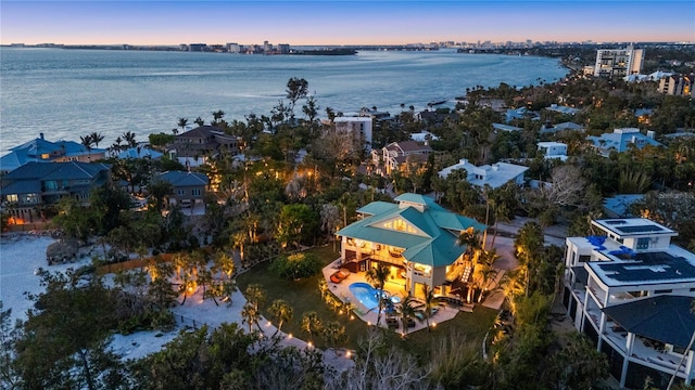 aerial view at dusk of a water view and view of pool