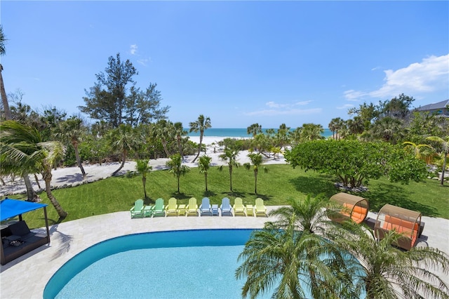 swimming pool with a water view, a patio area, and a yard