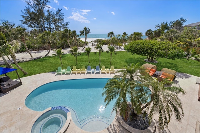 view of pool with a patio area, a yard, a water view, and a pool with connected hot tub