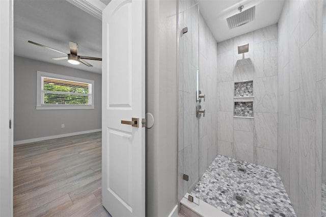 219 Vermont Ave, Saint Cloud, FL 34769 - bathroom with a tile shower, wood finished floors, a ceiling fan, and baseboards
