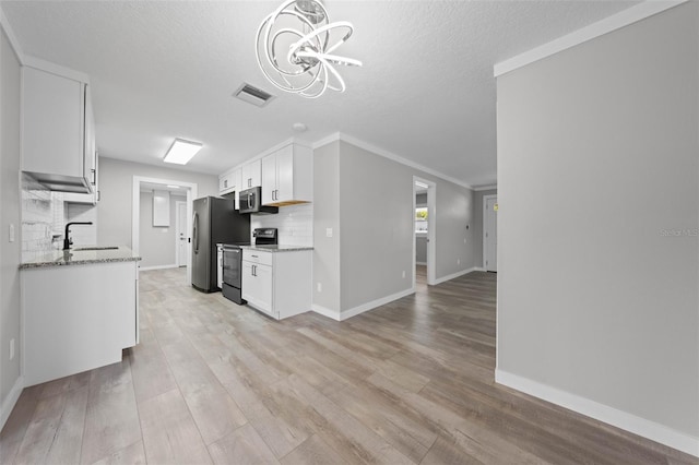 219 Vermont Ave, Saint Cloud, FL 34769 - kitchen with appliances with stainless steel finishes, a sink, a chandelier, tasteful backsplash, and white cabinetry