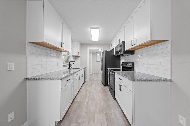 219 Vermont Ave, Saint Cloud, FL 34769 - kitchen featuring appliances with stainless steel finishes, a sink, baseboards, light stone counters, and light wood-type flooring