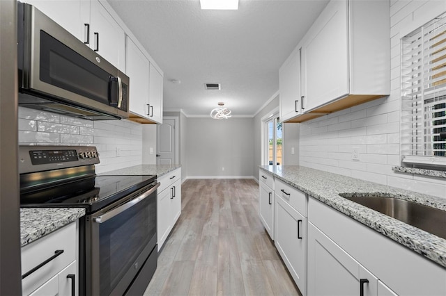 219 Vermont Ave, Saint Cloud, FL 34769 - kitchen featuring stainless steel appliances, ornamental molding, decorative backsplash, and white cabinetry