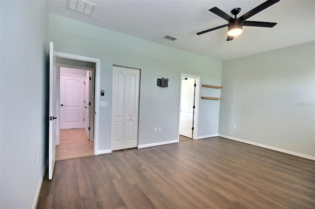 7311 64th St E, Palmetto, FL 34221 - unfurnished bedroom featuring dark wood-type flooring, baseboards, a closet, and a ceiling fan