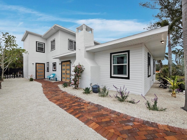 contemporary home featuring fence, a chimney, and french doors
