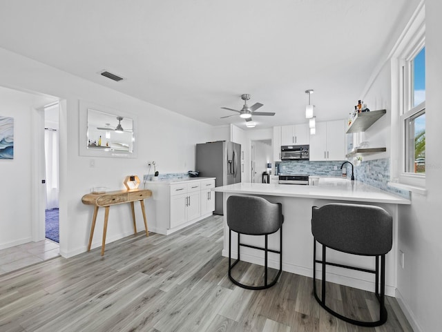 kitchen with appliances with stainless steel finishes, ceiling fan, open shelves, a peninsula, and light countertops