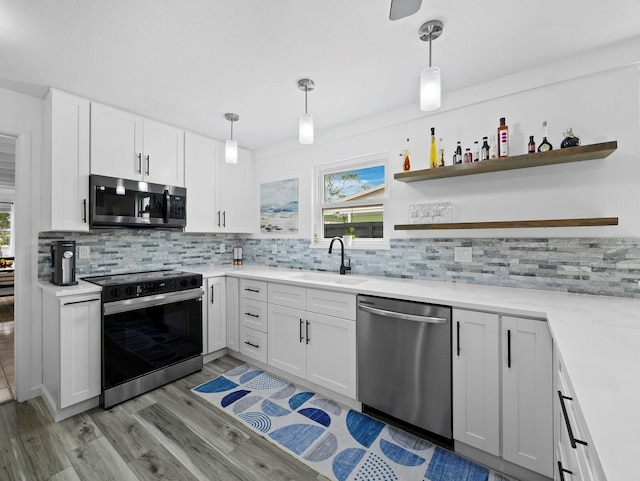 kitchen featuring stainless steel appliances, a sink, light wood finished floors, tasteful backsplash, and light countertops