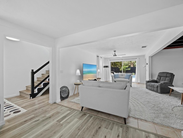 living room with stairs, wood finished floors, and ceiling fan