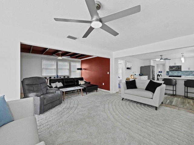 living room with ceiling fan, light wood-style flooring, and baseboards