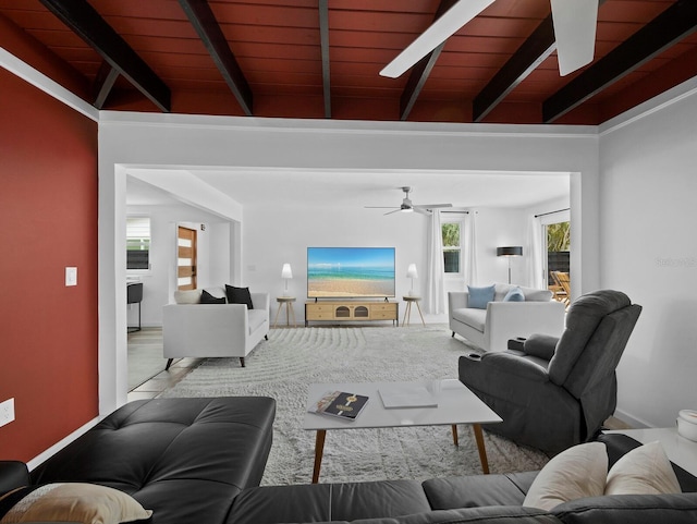 living room featuring ceiling fan, beamed ceiling, baseboards, and wood ceiling