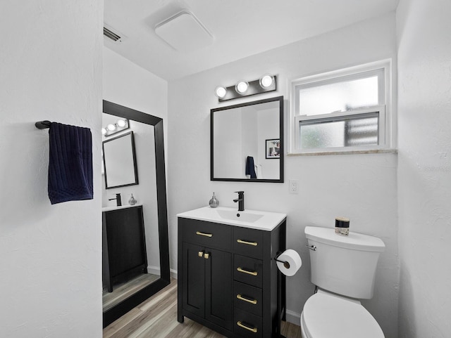 bathroom with wood finished floors, toilet, and vanity